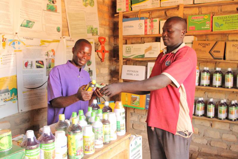 Francis attending to a customer at his agro-input shop in Mubende District.