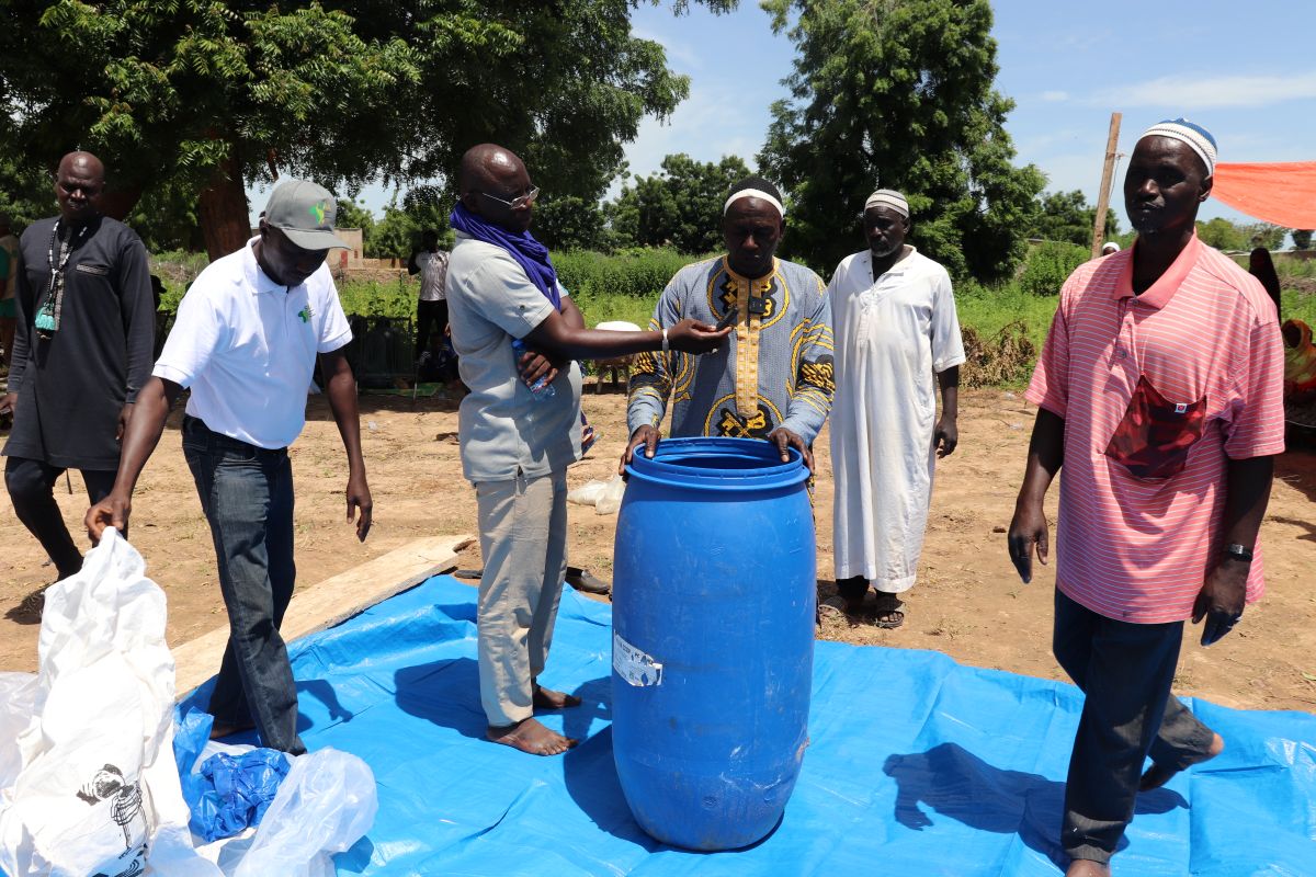 Practical session where farmers demonstrate the use of hermetic barrels for maize storage, placing grains inside for safe conservation