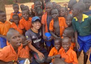 ウガンダの子どもたちに囲まれ笑顔のJOCV長谷川大起さん